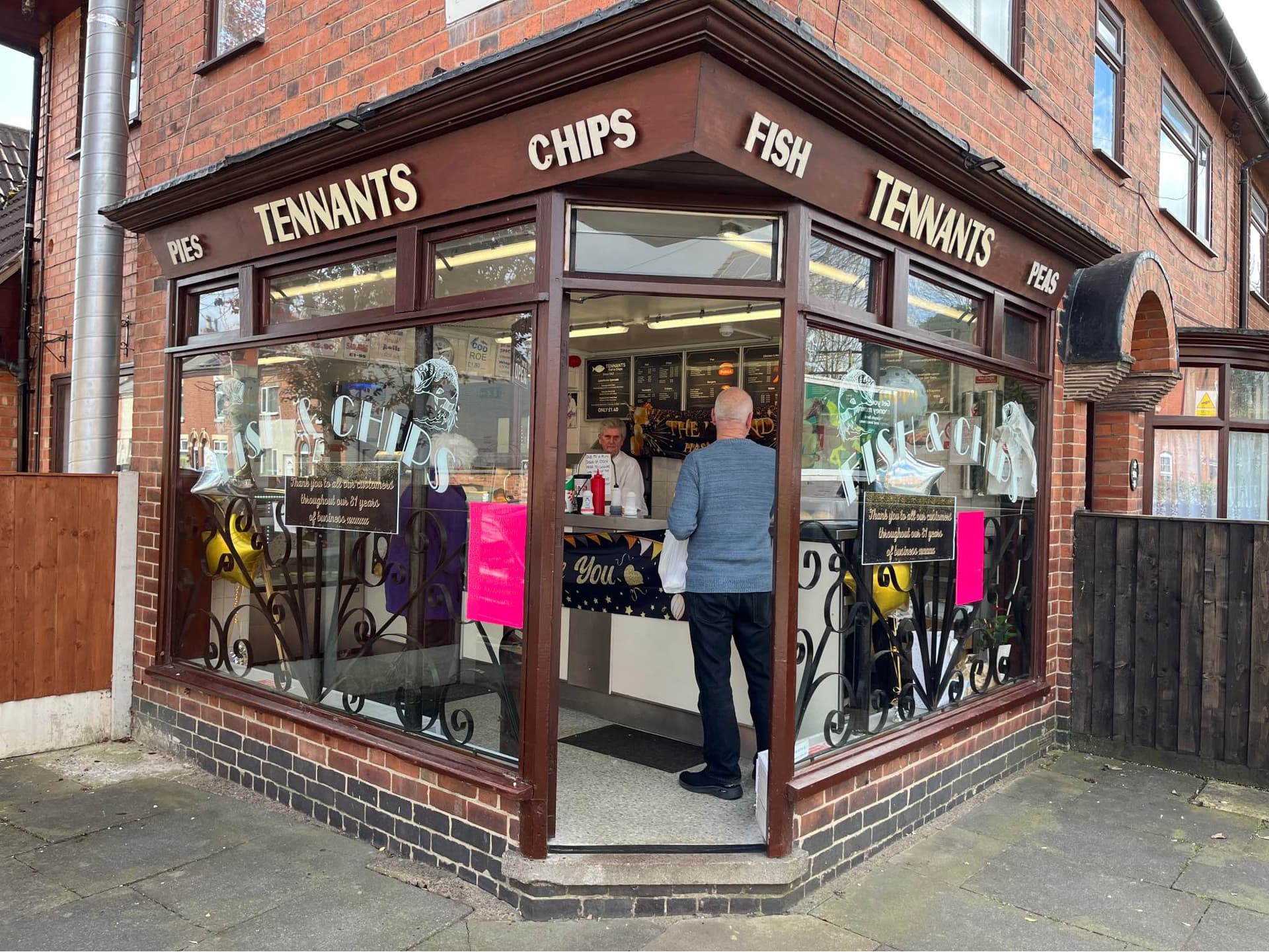 An external photo of Tennants Fish & Chips with customers inside.