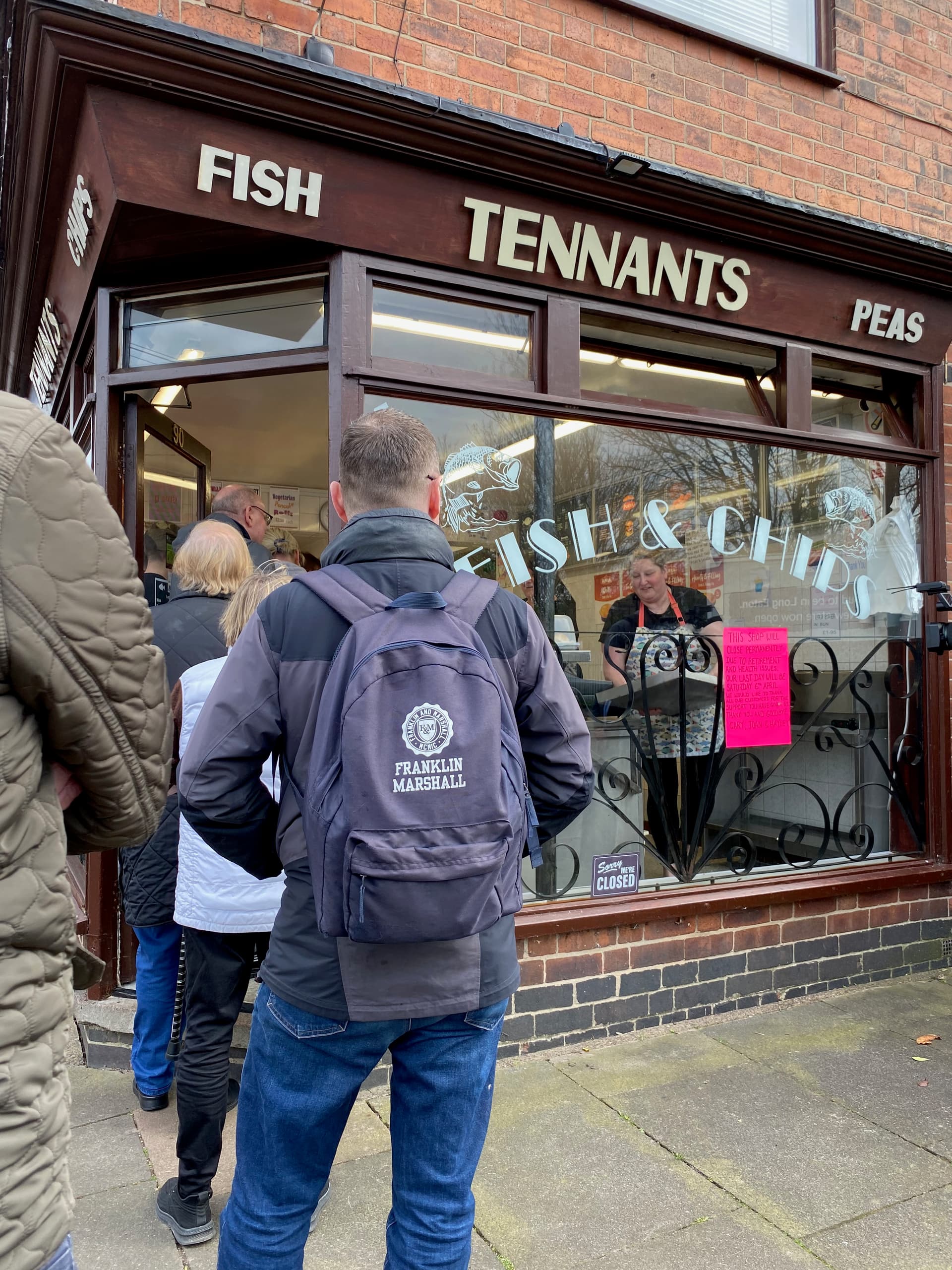 People queueing to visit Tennants Fish & Chips, Hayley Frearson serving customers in the window.