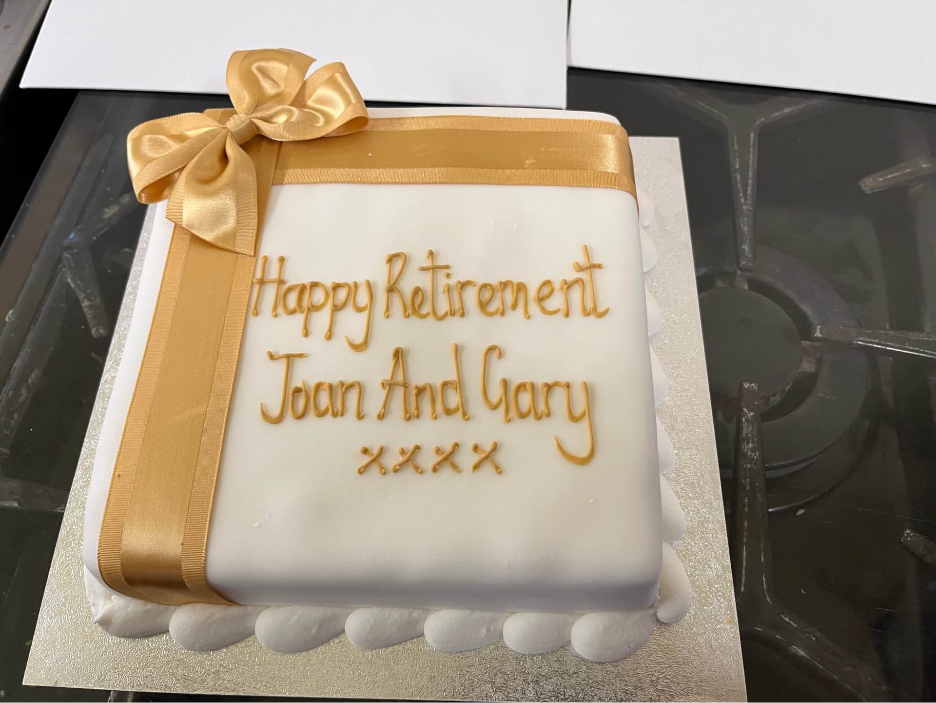 A cake stating 'Happy Retirement Joan And Gary xxxx'.